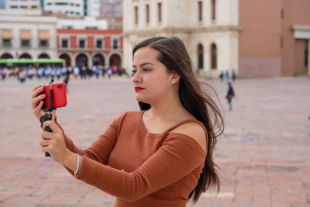 Jeune femme faisant du vlog vidéo avec smartphone et stabilisateur de cardan en plein air, vlogging dans les rues