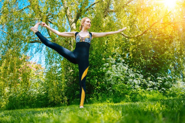 Jeune femme faisant du yoga asana dans le parc girl stretching exercice en position de yoga heureux et en bonne santé