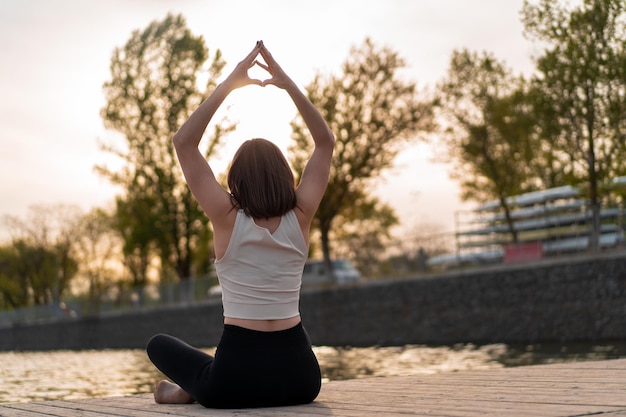 jeune femme faisant du yoga au bord du lac