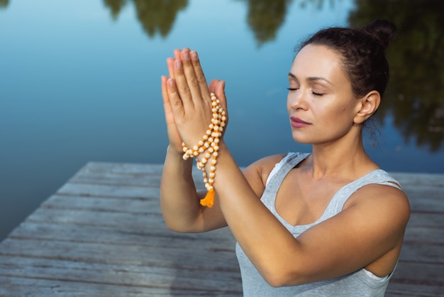 jeune femme faisant du yoga au bord du lac