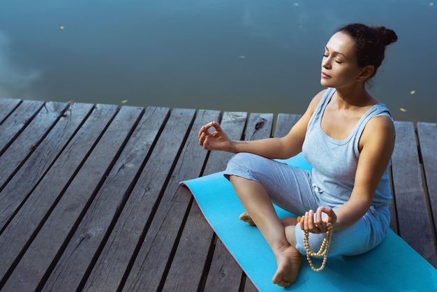 jeune femme faisant du yoga au bord du lac