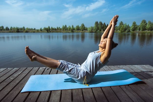 jeune femme faisant du yoga au bord du lac