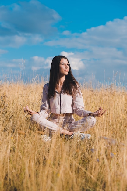 Jeune femme faisant du yoga dans le champ de blé