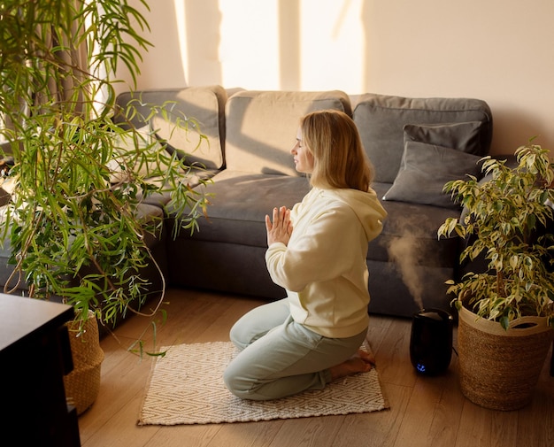 Jeune femme faisant du yoga à la maison assise sur le sol en asana