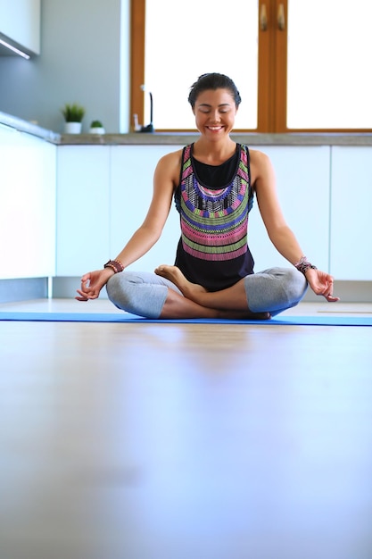 Jeune femme faisant du yoga à la maison dans la position du lotus