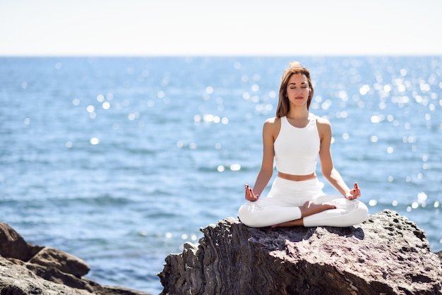 Jeune femme faisant du yoga à la plage