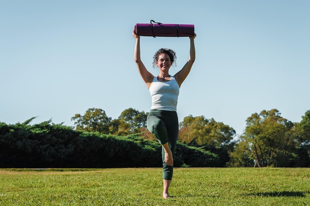 jeune femme faisant du yoga pose avec un tapis rose dans ses mains et un concept de yoga et de style de vie souriant