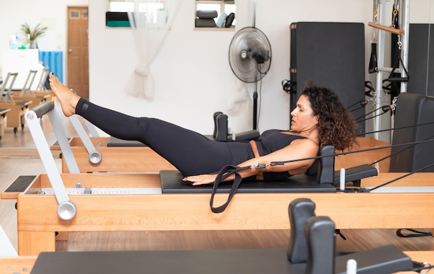 Photo jeune femme faisant de l'exercice sur des lits réformateurs pilates