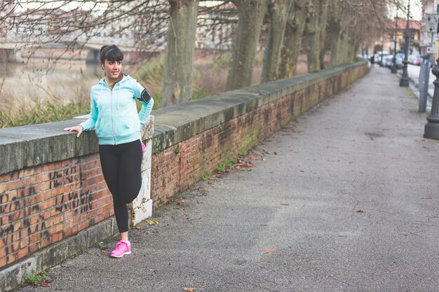 Photo jeune femme faisant des exercices d'étirement avant de faire du jogging.