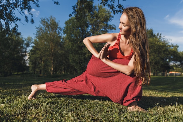 Jeune femme faisant des exercices de yoga dans le parc de la ville d'été