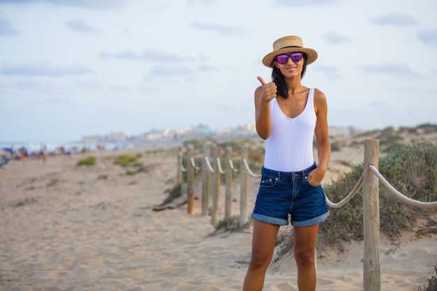 Jeune femme faisant un geste ok sur la plage