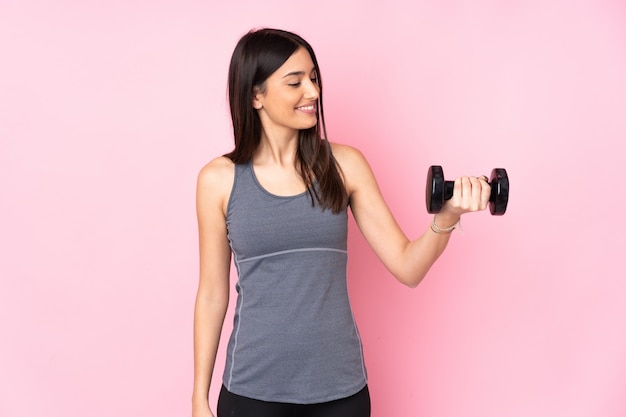 Jeune femme faisant de l'haltérophilie sur rose avec une expression heureuse