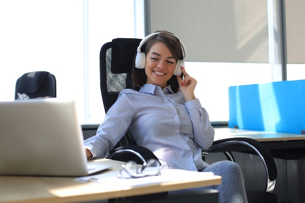 Jeune femme faisant une pause et écoutant de la musique dans des écouteurs assis sur le lieu de travail.