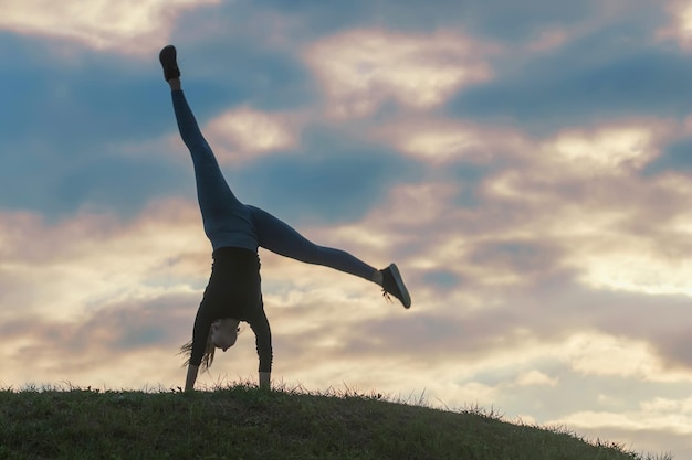 Jeune femme faisant la roue sur l'herbe Entraînement du matin