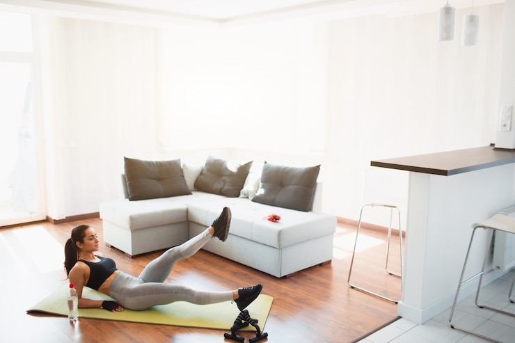 Photo jeune femme faisant une séance de sport dans la chambre pendant la quarantaine. fille bien formée avec un corps magnifique faisant des exercices de jambes de ciseaux sur le tapis. s'appuyant sur les mains. étirement des jambes de haut en bas.