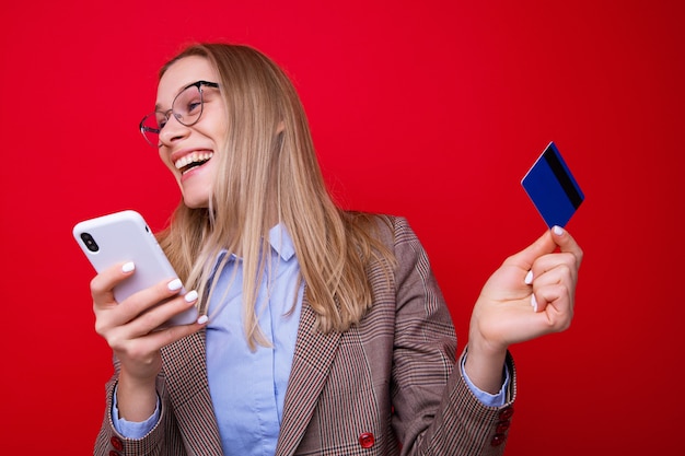 Une jeune femme fait des achats en ligne sur un mur rouge