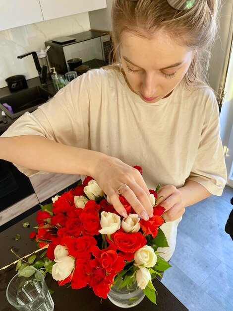 Une jeune femme fait un bouquet de roses rouges