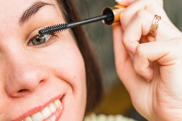 Une jeune femme fait du maquillage Fille peint ses cils avec du mascara