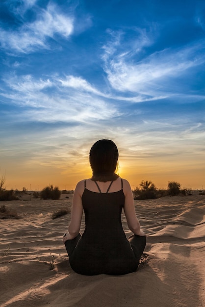 Une jeune femme fait du yoga dans le désert.