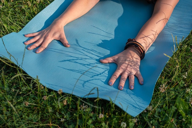 Une jeune femme fait du yoga dans le parc sur l'herbe.