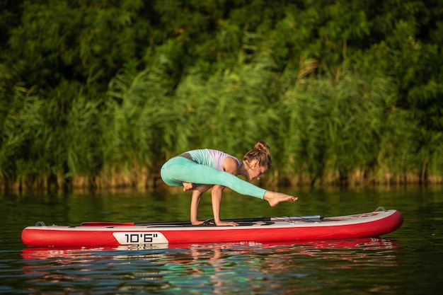 Une jeune femme fait du yoga sur un stand up paddle board SUP sur un magnifique lac ou une rivière. Le concept d'un mode de vie sain. Sport. Yoga. Passe-temps