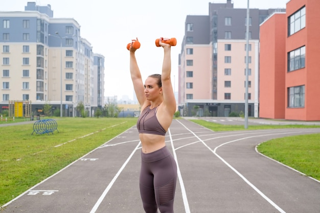 Une jeune femme fait un entraînement sportif au stade à l'extérieur avec des équipements sportifs. Modes de vie et exercice d'entraînement pour la musculation et la santé.