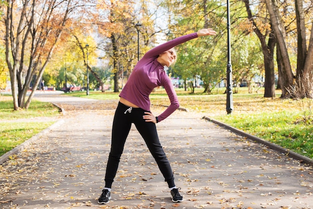 Jeune femme fait des exercices dans le parc Sports à l'extérieur en automne