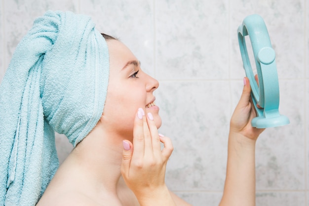 Jeune femme fait un massage du visage avec les mains dans la salle de bain.