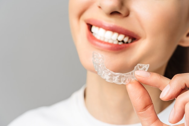 Photo une jeune femme fait une procédure de blanchiment des dents à domicile avec un plateau de blanchiment avec du gel