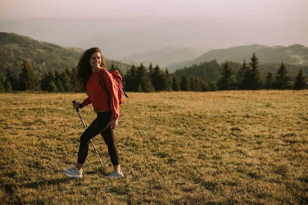 Jeune femme fait une randonnée panoramique sur une colline portant tout son équipement nécessaire dans un sac à dos