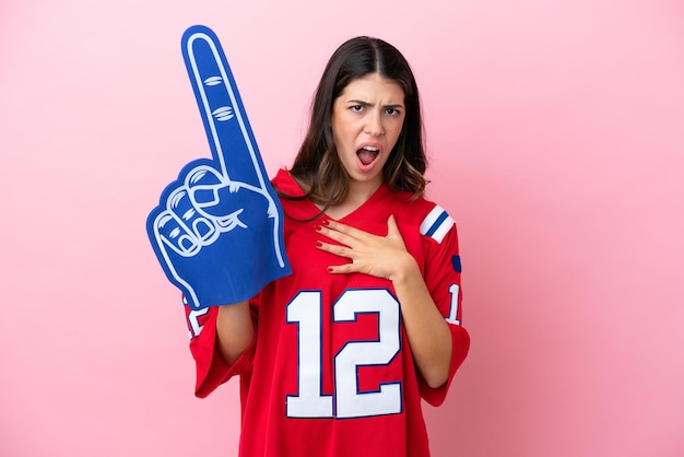 Jeune femme fan italienne avec une main en mousse isolée sur fond rose surprise et choquée en regardant à droite