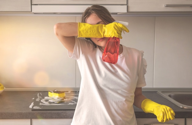 Jeune femme fatiguée après avoir nettoyé la cuisine, photo d'arrière-plan de l'entretien de l'appartement