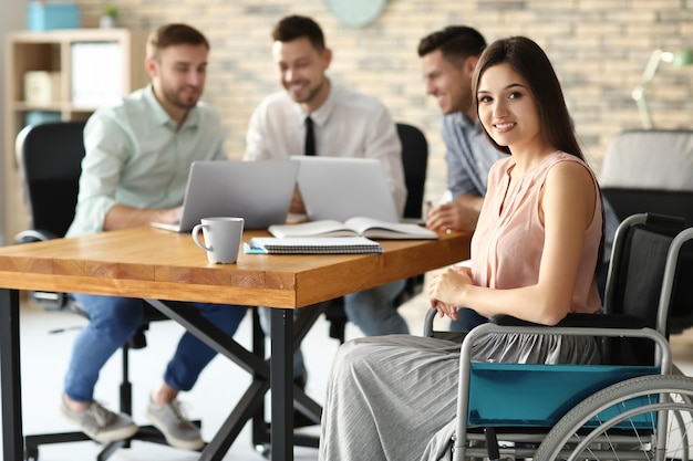 Jeune femme en fauteuil roulant et collègues sur le lieu de travail