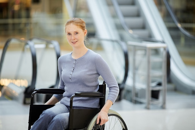 Jeune femme en fauteuil roulant dans un centre commercial