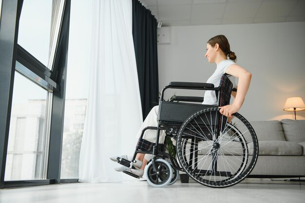 Jeune femme en fauteuil roulant à la maison dans le salon