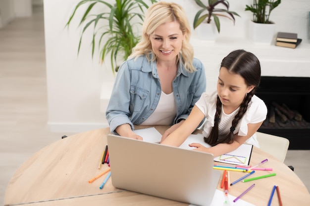 Jeune femme avec une fille à l'aide d'un ordinateur portable.