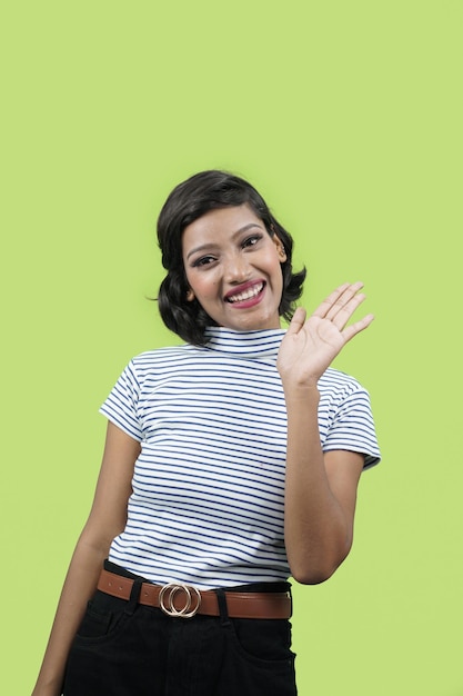 Jeune femme ou fille indienne renonçant à dire bonjour heureux et souriant, geste de bienvenue amical