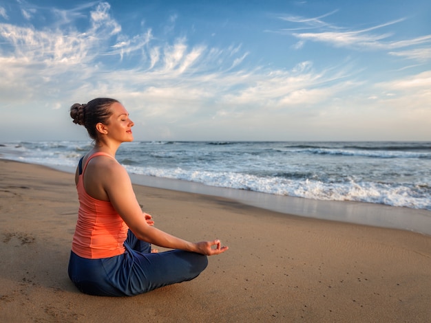 Jeune femme fit sportive faisant du yoga à l'extérieur sur la plage