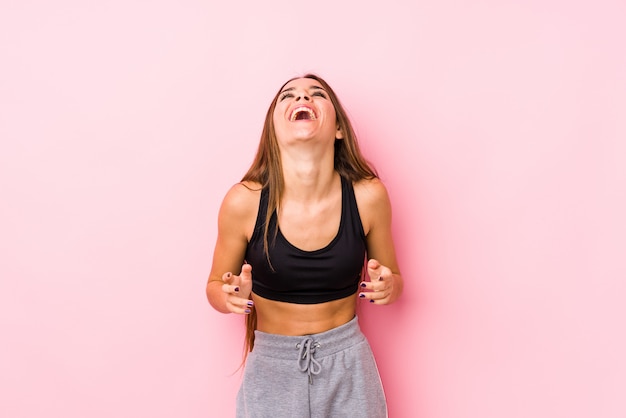 Jeune femme fitness caucasien posant dans un mur rose joyeux rire beaucoup. Concept de bonheur.