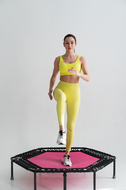 Jeune femme de fitness en tenue de sport sautant sur un trampoline de sport