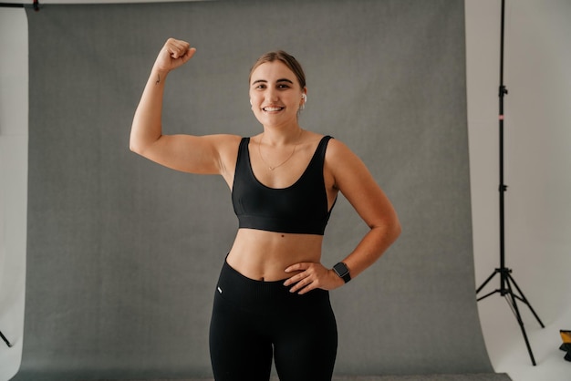 Jeune femme fléchissant les muscles de ses bras dans un studio