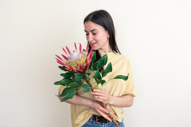 Une jeune femme avec fleur de protea sur fond blanc