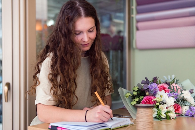 Jeune femme fleuriste accepte une commande pour un bouquet de fleurs en milieu de travail