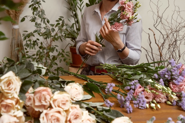 Jeune femme fleuriste dans son studio faisant un beau bouquet