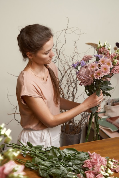 Jeune femme fleuriste dans son studio faisant un beau bouquet