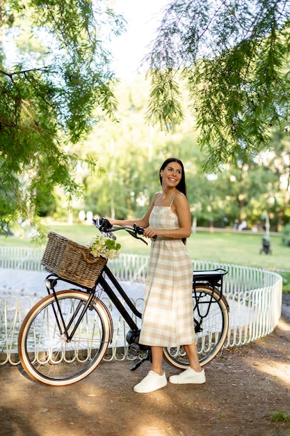 Jeune femme avec des fleurs dans le panier de vélo électrique