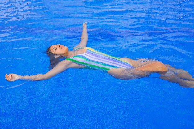 Jeune Femme Flottant Dans La Piscine