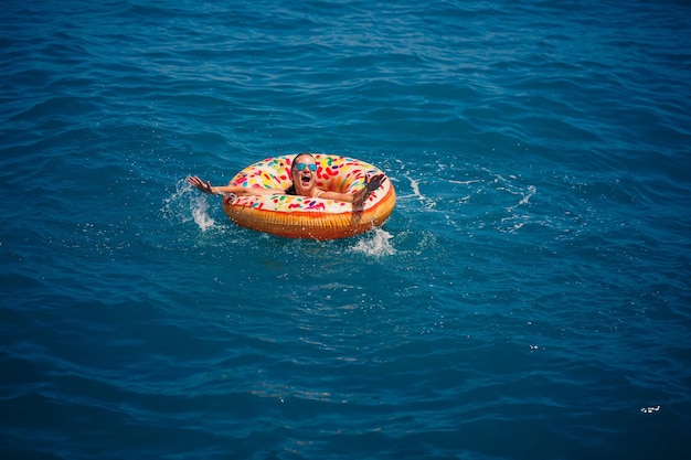 Jeune femme flottant sur un gros beignet gonflable dans la mer turquoise transparente Vue d'une dame élancée se détendre en vacances en Turquie Egypte Mer Méditerranée