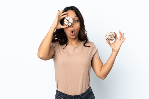 Jeune femme sur fond blanc isolé tenant un beignet dans un oeil