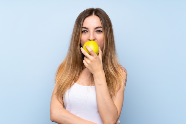 Jeune femme sur fond bleu isolé avec une pomme